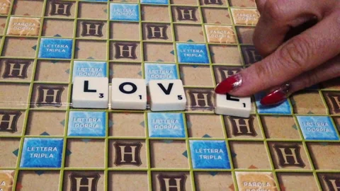 Closeup of woman's hands composing love word on board game. New York, 12/31/2020 Stock Footage 145826208