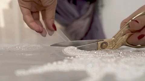 A closeup of woman's hands cutting out sequined and beaded lace  Stock Footage 99052277
