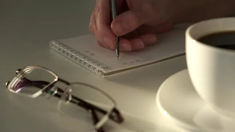 Closeup of woman's hands journaling in a white notebook on a white table at home Stock Footage 260759500