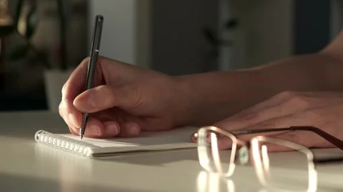 Closeup of woman's hands journaling in a white notebook on a white table at home Stock Footage 264187073