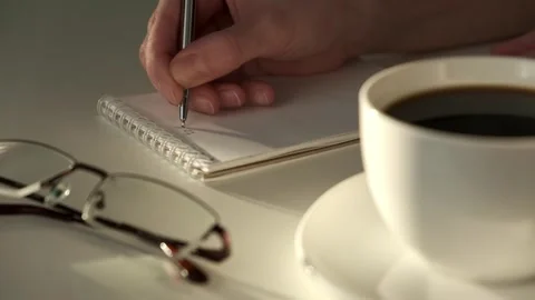 Closeup of woman's hands journaling in a white notebook on a white table at home Stock Footage 267916200