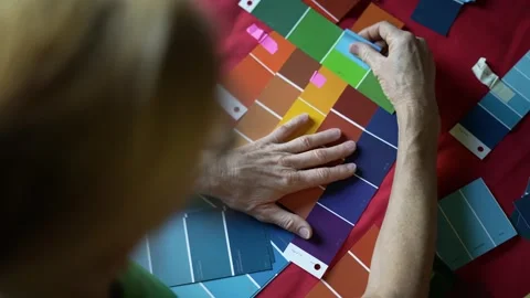 Closeup of a womans hands as she compares sample paint swatches and considers Stock Footage 274273845