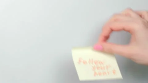 Closeup woman's hands stick yellow sticker paper sheets with words follow your Stock Footage 88307553