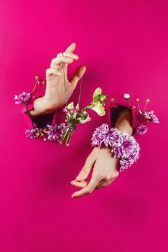 Closeup of woman's hands through torn paper holding bottle with bouquet on a  Stock Photos
