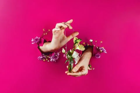 Closeup of woman's hands through torn paper holding bottle with bouquet on a  Foto stock