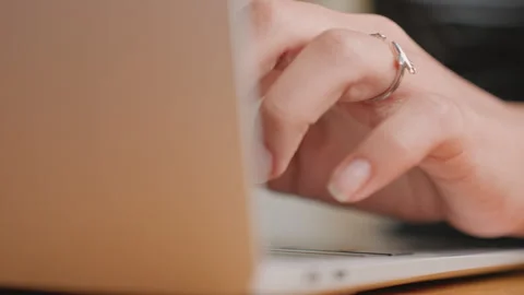 Closeup womans hands typing hotel desk, laptop keys and delicate ring visible Stock Footage 330532489