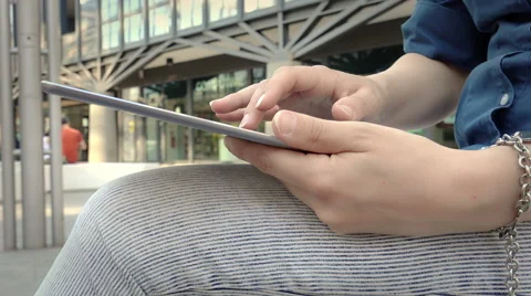 Closeup on woman's hands using tablet computer sitting in the city center  Video stock 64800237