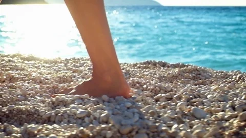 Closeup woman's legs walking on a beach at sunset over a sea. Stock Footage 71293398