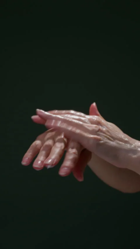 Closeup of womens hands rubbing moisturizing cream on dark green background Video stock 306259710