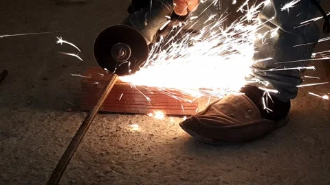 Closeup of worker cutting steel bar with grinder sparks flying as iron is ground Stock Footage 332758848