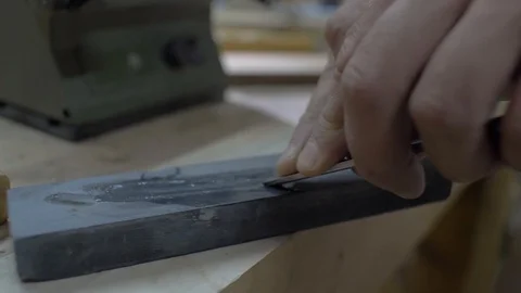 Closeup worker grinds a chisel on a grinding stone. Hands sharpen a chisel Stock Footage 116528980