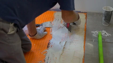 Closeup of worker installing ceramic tiles on new bathroom floor Stock Footage 95996068