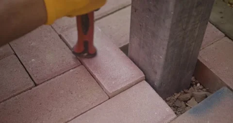 Closeup of a worker Installing Paving Stone Around Post with Rubber Mallet Stock-Footage 308682764