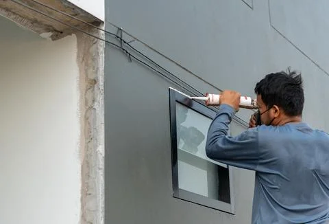 Closeup worker installing the windows with gun silicone. Stock Photos