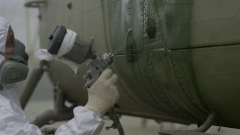 Closeup Worker Paints Helicopter with Sprayer in Hangar Stock Footage 72565621