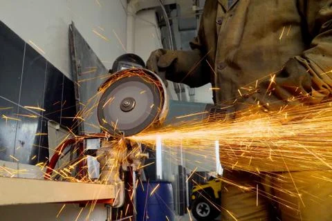 Closeup of worker using a grinder cuts metal in a workshop Stock Photos