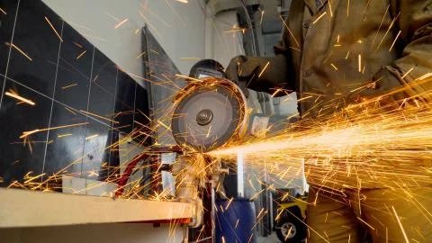 Closeup of worker using a grinder cuts metal in a workshop Stock Photos