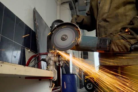 Closeup of worker using a grinder cuts metal in a workshop Stock Photos