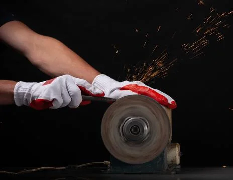 Closeup worker using grinding machine for metal finishing with flash of spark Stock Photos