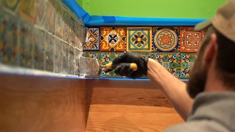 Closeup of worker using spatula float to wipe off excess grout from Stock Footage 101434747