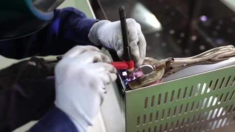 Closeup of worker welding small hinge hardware piece with torch and white gloves Vídeo Stock 345046914