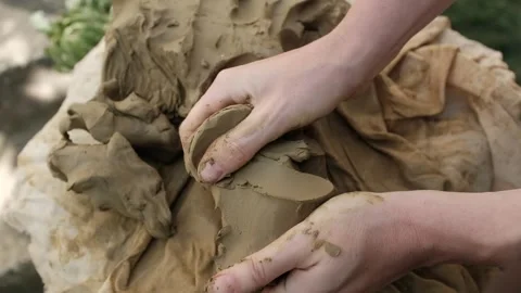 Closeup of working with wet clay. Hands separate small lumps of clay. Stock Footage 316920632