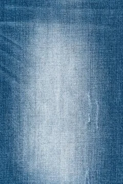 Closeup of worn blue denim texture. Faded jean fabric background with visible Stock Photos