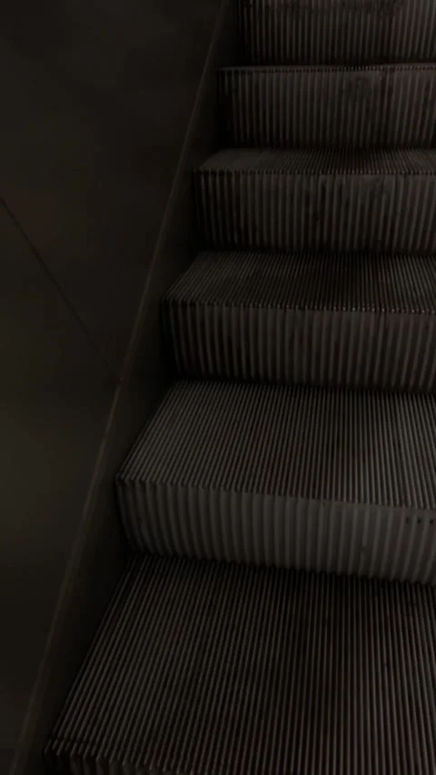 Closeup of worn steps on shadowed escalator with nighttime urban activity Stock Footage 335368147