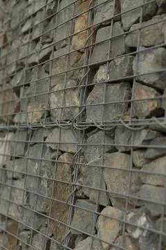 Closeup of woven wire grid with stacked stones creating pattern Stock Photos