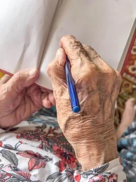 Closeup wrinkled hand taking note on a notebook Stock Photos