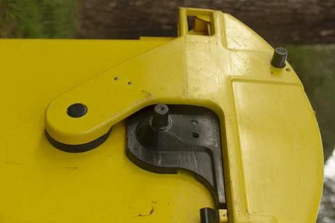 Closeup of yellow bin latch with background hints of surroundings Stock Photos