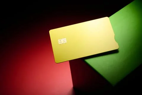 Closeup of a yellow debit card with a microchip on a red and green table. Stock Photos