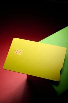 Closeup of a yellow debit card with a microchip on a red and green table. Stock Photos