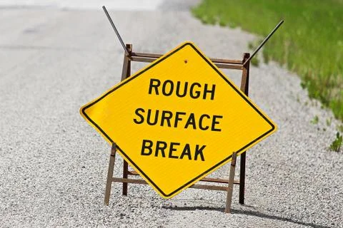 Closeup of a yellow rough surface break sign on pavement Stock Photos