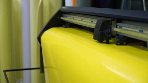 Closeup yellow sheet moves through large format plotter 스톡 동영상 101287830