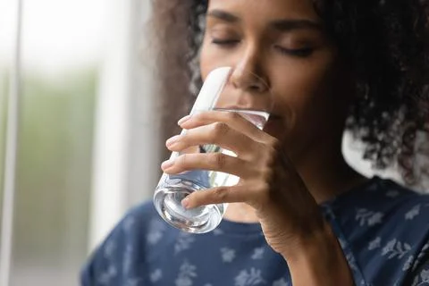 Closeup of young african woman drinking cool water from glass Stock Photos