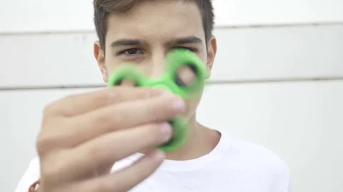 Closeup of young boy playing with fidget spinner flicking and holding the spi Stock Footage 81429589