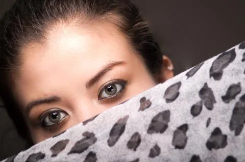 Closeup young brunette model posing with grey brown scarf covering half her face 스톡 사진