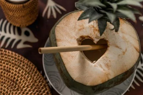 Closeup of young coconut with straw on the table in restaurant. Stock Photos