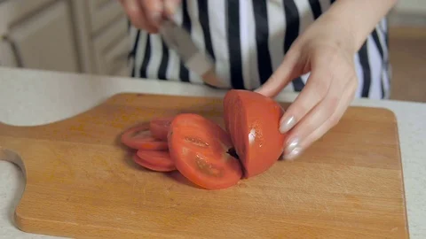 Closeup a young couple in the kitchen slicing tomatoes on a cutting board Stock Footage