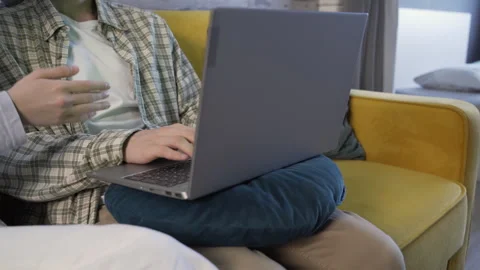 Closeup young couple sitting on the couch, a man typing on a laptop Stock Footage 259793693
