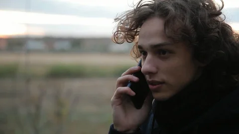 Closeup of young cute man talking on the phone with friend outdoors Stock Footage 97537845
