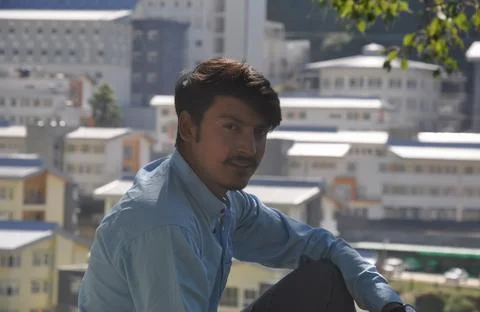 Closeup of a young guy looking at camera sitting outside with buildings Stock Photos