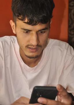 Closeup of a young guy using phone while sitting indoors Stock Photos