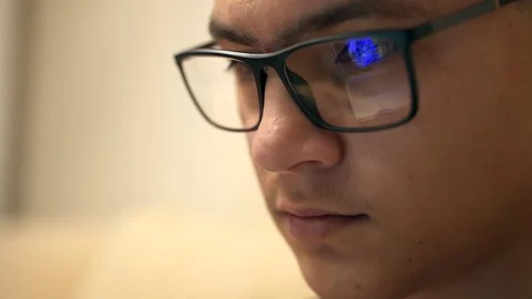 Closeup of young hipster guy wearing glasses and working at night via laptop at Stock-Footage 105503108