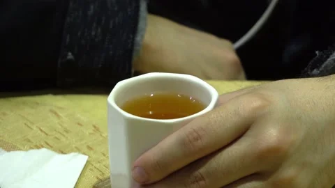 Closeup of a young man with glasses drinking jasmine tea in a small white cup in 스톡 동영상 161447274