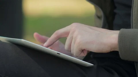 Closeup of a young man with glasses sitting on a park bench, working in the Stock Footage