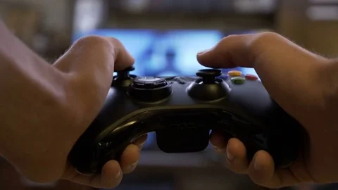 Close-up. The gamer holds a gamepad in his hands. Plays video