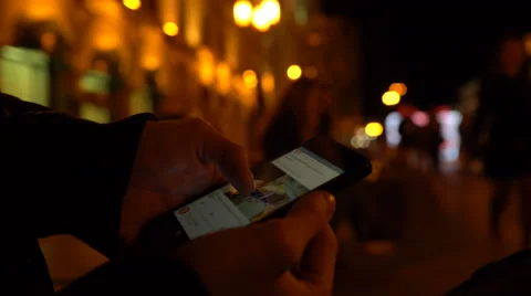 Closeup of young man hands scrolling internet on phone. Night illuminated city Stock Footage 69067483