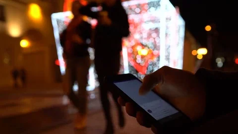 Closeup of young man hands scrolling internet on phone. Night illuminated city Stock Footage 69072293